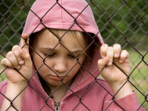 悲伤的女孩在篱笆旁