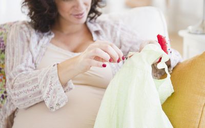 孕妇正在缝制婴儿衣服上的纽扣