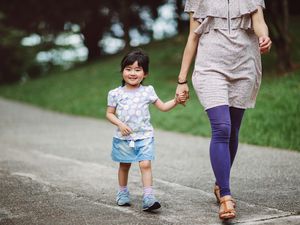 Little girl strolling in park with mom joyfully