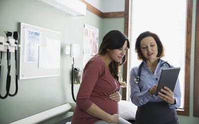 Doctor and pregnant woman looking at digital tablet