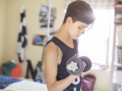 Teenage boy exercising with dumb bell