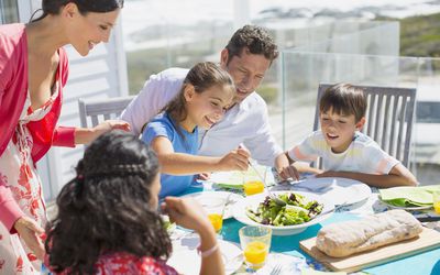 Family eating lunch at table on sunny patio