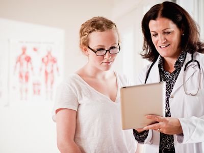 Doctor shows woman health info on digital tablet