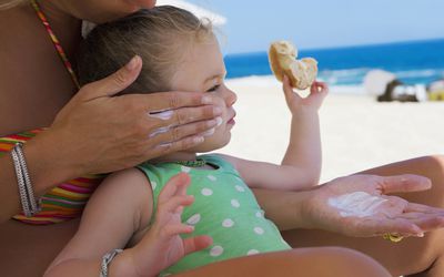 一位妇女在海滩上给她的小女儿涂防晒霜