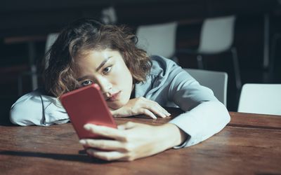 悲伤的年轻女子在使用智能手机