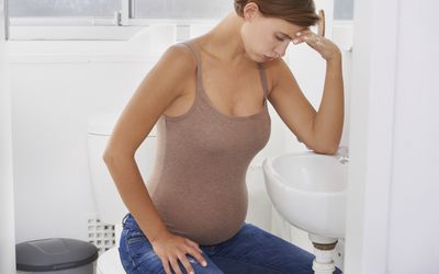 孕妇在浴室看起来很担心或恶心