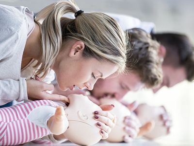 Doctor practicing infant CPR on training dummies