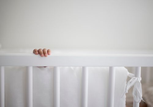 Cropped Image of Baby Hand In Crib At Home