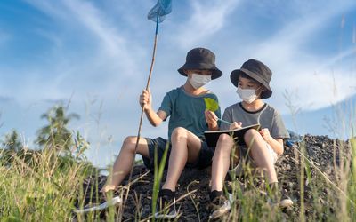 two boys looking at nature wearing bucket hats and masks