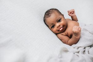 美丽的非裔美国新生儿小男孩只有几周大襁褓在奶油色柔软的毯子复制空间