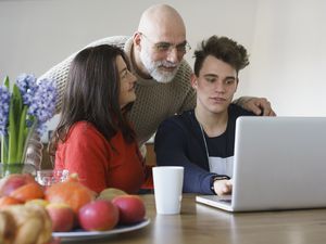 Family discussing while looking at laptop on table at home