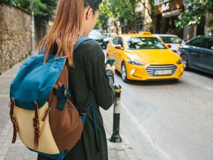 college student checking phone waiting on cab