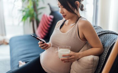 pregnant woman sitting on the couch drinking milk