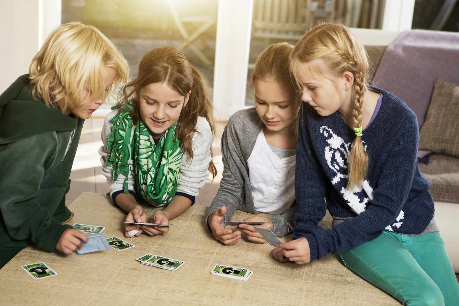 Four children playing card game in living room