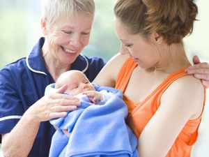 Proud grandmother watches daughter holding newborn grandson