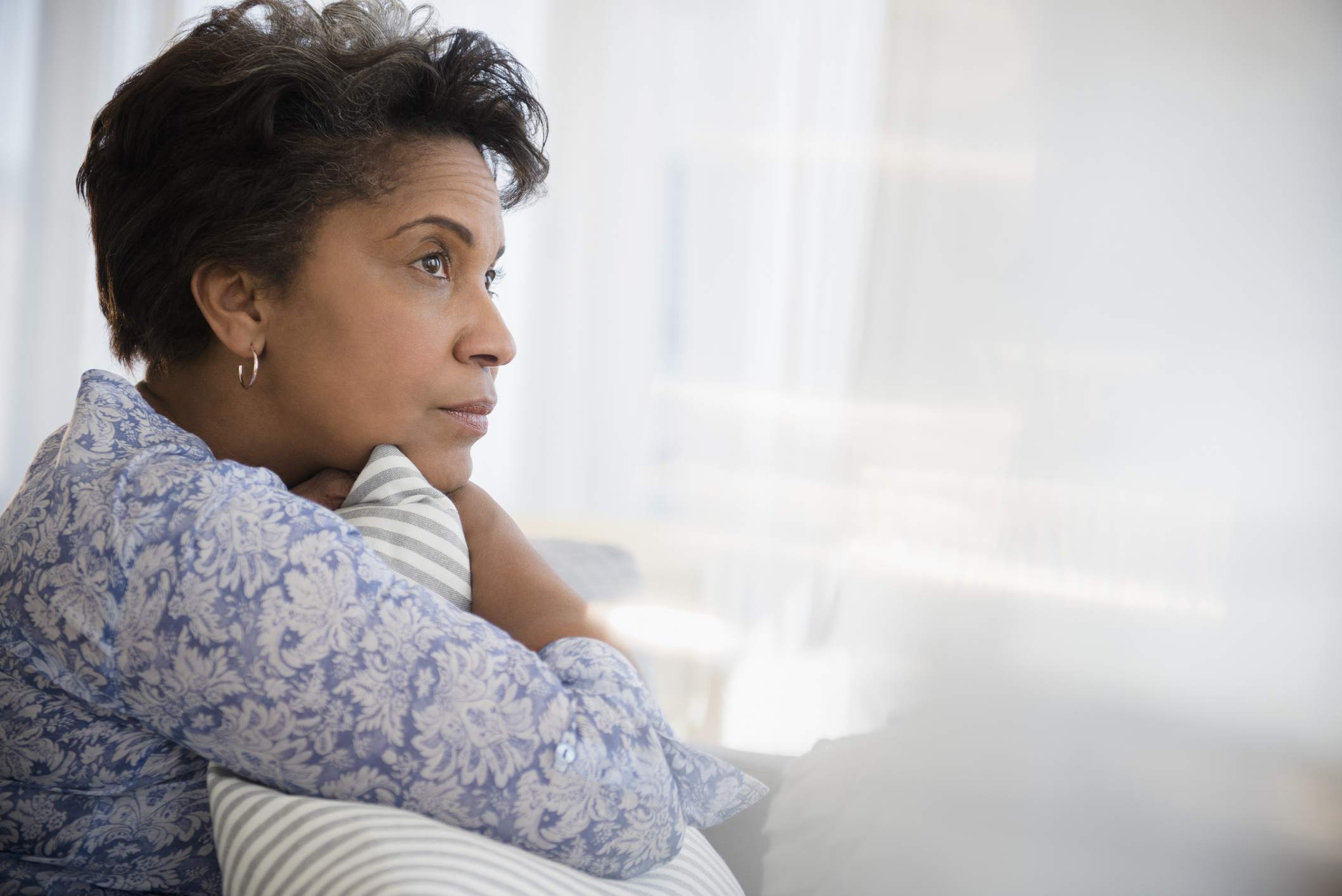 Pensive older Black woman clutching pillow