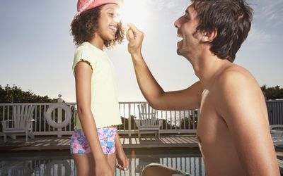 Man and girl applying sun block to noses