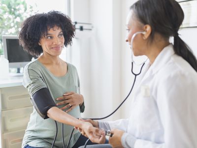 African American doctor taking pregnant woman's blood pressure