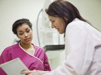 Mature doctor using digital tablet to explain to female patient