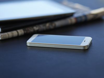 cell phone on table next to newspaper