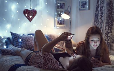 两个青少年躺在床上看手机
