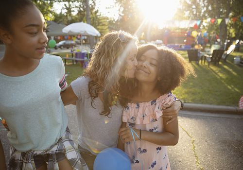 Affectionate mother kissing daughters cheek at party