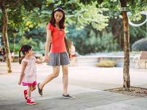 妈妈和蹒跚学步的孩子在公园里愉快地散步