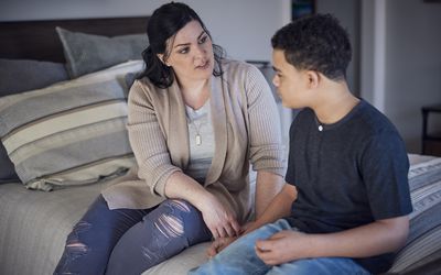 Mom and son sitting on bed talking