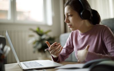 十几岁的女孩戴着耳机在家上网络学校的课