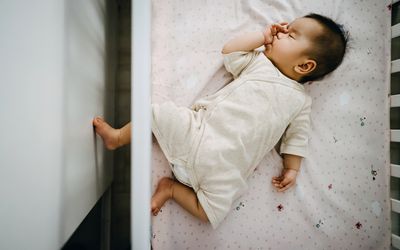 可爱的亚洲女婴吮吸拇指，而和平地睡在婴儿床- stock照片