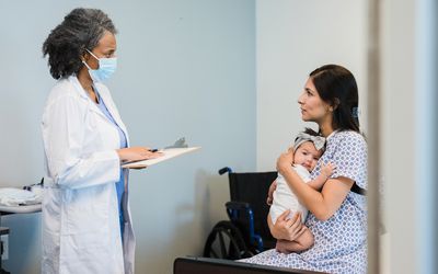 一位医生正和一位抱着婴儿的妇女交谈
