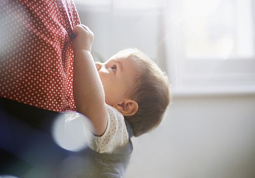 蹒跚学步的孩子紧紧抓住妈妈的裙子