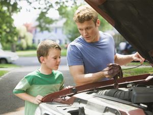 boy watching father repair car