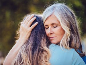 Grandmother lovingly embracing and holding teenage granddaughter