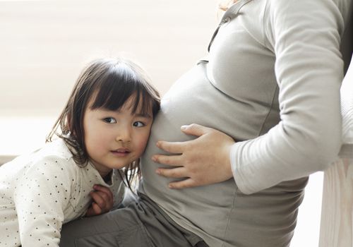 Little girl listening to mother's pregnant belly