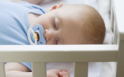 Baby sleeping in crib with pacifier