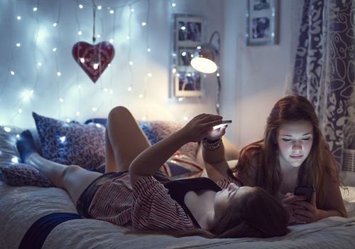 两个女孩在床上玩手机