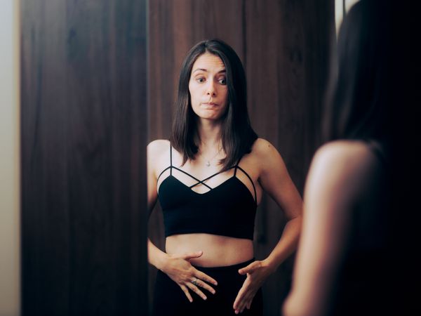 Woman Looking in Mirror Touching Belly