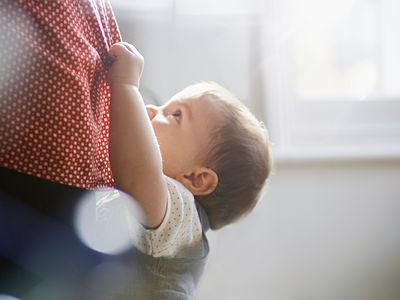 toddler hanging on to mother's dress