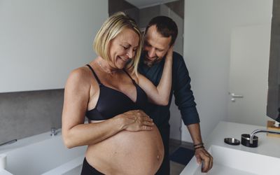 幸福的成熟怀孕夫妇在浴室里看着准妈妈的肚子