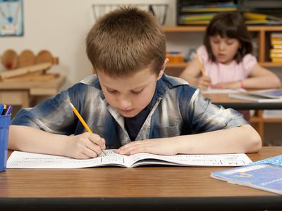 young boy and girl taking test at desks in classroom