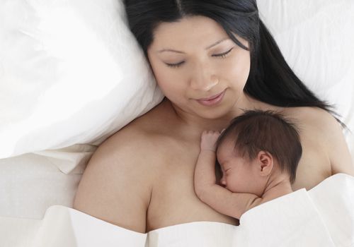 Mother holding newborn infant on her chest