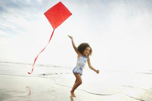 在沙滩上拿着风筝奔跑的女孩