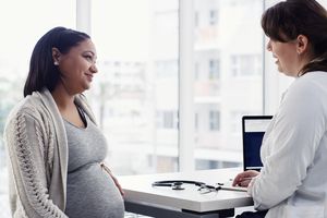 怀孕的年轻妇女正在咨询她的医生＂width=