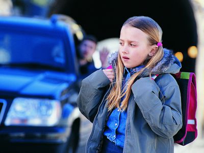 Man in car waving to apprehensive girl standing in the street