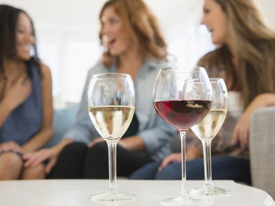 Women drinking wine and talking on sofa in living room