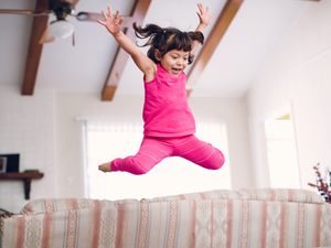 A little girl jumping on the furniture