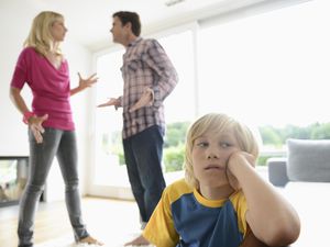 Boy looking away as parents argue behind him