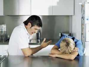 Father scolding his middle school aged son in the kitchen