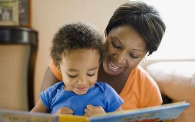 妈妈给她的孩子读一本书。＂width=